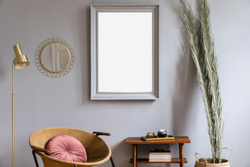 Stylish and luxury interior with design honey yellow armchair, gray mock up frame, palm, gold mirror and lamp. Retro small table with elegant accessories and books. Modern home decor of living room