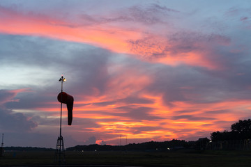 BADUNG/BALI-APRIL 14 2019: Wind sock under at the dawn under the red orange glowing sky with cirrus...