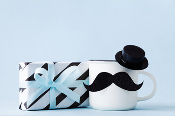 Creative breakfast on Happy Fathers Day with gift or present box and funny face from cup of coffee, hat and moustache.