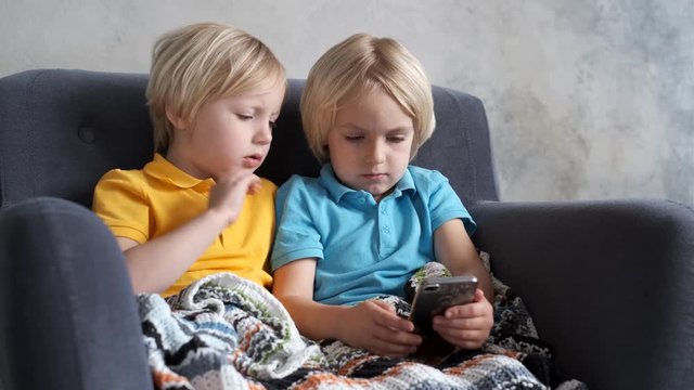 Brothers are watching or playing or learning something in a smartphone