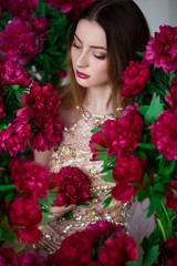 Portrait of beautiful brunette girl with red peonies. Happy boho woman portrait with peony flowers. Creative floral photo.