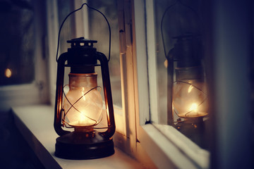 Vintage kerosene lamp stands on a white windowsill