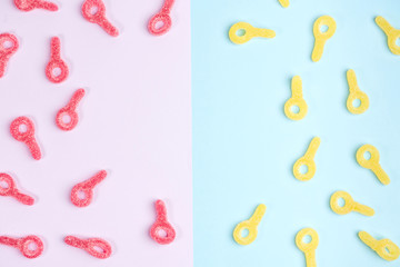 Space for text on background of jelly candies. Red and yellow gummy candies,  on pink and blue backgrounds. Top view.