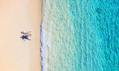 Aerial view of a people couple on the beach on Bali, Indonesia. Vacation and adventure. Beach and turquoise water. Top view from drone at beach, azure sea and relax couple. Travel and relax - image © biletskiyevgeniy