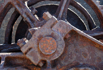 close up of old brown rusty obsolete broken machinery with large wheel and bolts