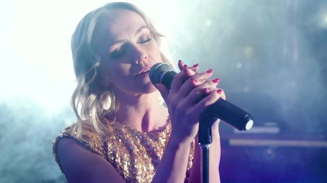 Portrait of a young woman singing on smoky stage.