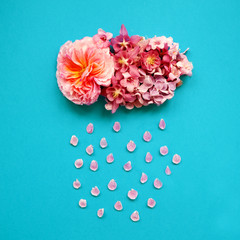 cloud with rain made of colorful spring flowers and leaves. Arrangement of flowers and on blue background. Blooming flowers concept. Flat lay. Minimal nature. Top view