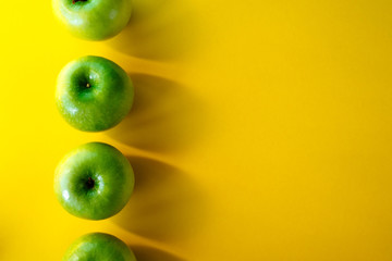 Summer pattern of fresh green apples on yellow background. Copy spase