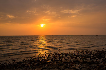 Bright sunset with large yellow sun under the sea surface. sunrise in the sea. Beautiful sunset above the sea. Tropical sunset on the beach.