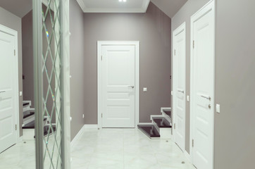 Empty corridor with white dalle and newly painted brown wall in background with doors