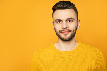 Obraz premium Close up portrait of happy handsome man in yellow is posing over orange background
