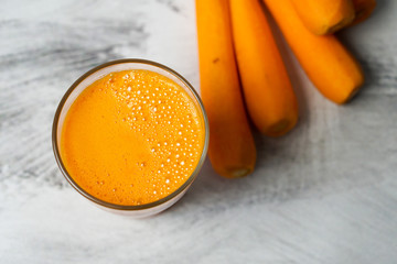 Fresh carrot juice in a glass on a dark white background