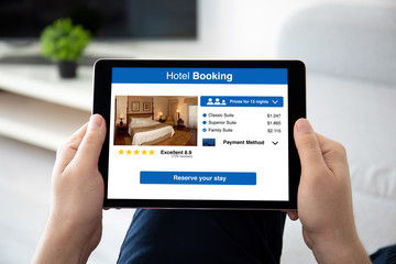 man hands holding computer tablet with app hotel booking