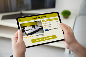man hands holding computer tablet with app hotel booking