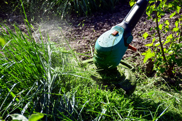 The simple mThoments of life, ordinary work in the garden -  man trimming grass with heavy-duty trimmer in the garden, suitable for trimming long lawn edges and larger hard-to-access areas. Man mows . - 267441805