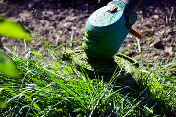 The simple mThoments of life, ordinary work in the garden -  man trimming grass with heavy-duty trimmer in the garden, suitable for trimming long lawn edges and larger hard-to-access areas. Man mows .