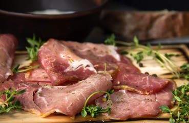 delicious pork bacon sliced ​​into strips on a wooden background with spices and fresh thyme. A...