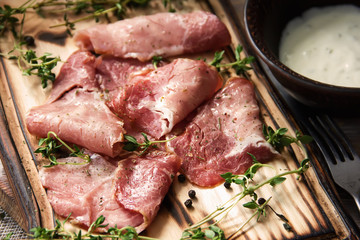 delicious pork bacon sliced ​​into strips on a wooden background with spices and fresh thyme. A serving of low-fat succulent farm meat pork. Food Photography