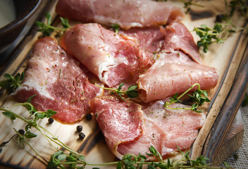 delicious pork bacon sliced ​​into strips on a wooden background with spices and fresh thyme. A serving of low-fat succulent farm meat pork. Food Photography
