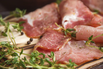 delicious pork bacon sliced ​​into strips on a wooden background with spices and fresh thyme. A serving of low-fat succulent farm meat pork. Food Photography
