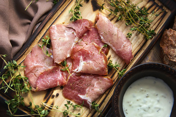 delicious pork bacon sliced ​​into strips on a wooden background with spices and fresh thyme. A serving of low-fat succulent farm meat pork. Food Photography