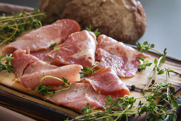 delicious pork bacon sliced ​​into strips on a wooden background with spices and fresh thyme. A serving of low-fat succulent farm meat pork. Food Photography