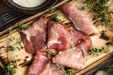 delicious pork bacon sliced ​​into strips on a wooden background with spices and fresh thyme. A serving of low-fat succulent farm meat pork. Food Photography