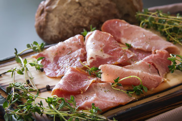 delicious pork bacon sliced ​​into strips on a wooden background with spices and fresh thyme. A serving of low-fat succulent farm meat pork. Food Photography