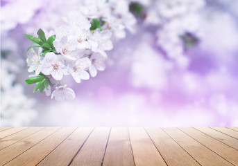 Empty wooden table, natural delicate flowers in the background, sun rays. Light delicate floral background pattern