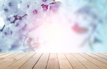 Empty wooden table, natural delicate flowers in the background, sun rays. Light delicate floral background pattern