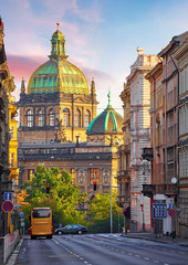 Street in Prague, Czech Republic. Cityscape with road and view at dome of national museum building. Transport and bus at crossroad. Dawn early morning in centre of city. - obrazy, fototapety, plakaty