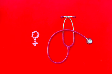 diagnostic and cure of gynaecological disease with stethoscope and female symbol on red background top view