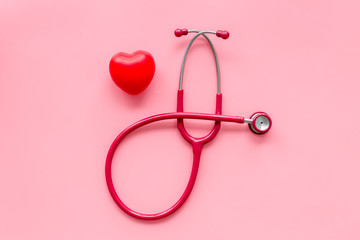 diagnostic and cure of cardiac disease with stethoscope and heart on pink background top view