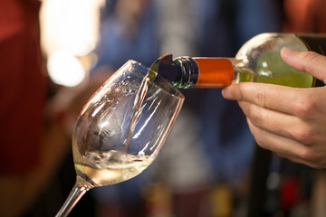 White wine is poured into a glass. Festive party