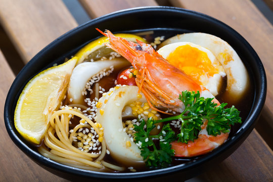 Image of spicy pan-Asian soup with squid, shrimp, egg noodles and sesame