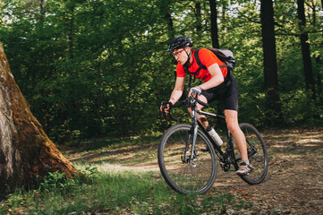 Naklejka premium Mountain biker riding on bike in spring inspirational forest landscape. Man cycling MTB on enduro trail track. Sport fitness motivation and inspiration.