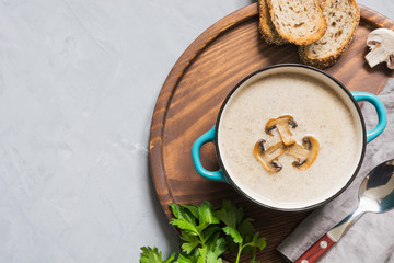 Delicious mushroom champignon soup on grey concrete table. Horizontal mockup, view from above. Space for text.