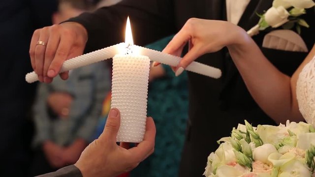Brides light preists candle in church on wedding ceremony. Close up.