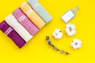Obraz na płótnie Canvas preparing for laundry with washing powder and towels on yellow background top view