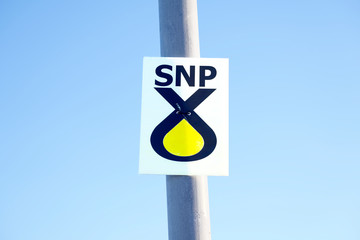 SNP Scottish National Party icon yellow campaign sign on lamp post against plain clear blue sky
