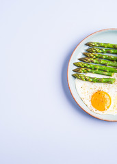 Fried eggs with steamed asparagus flat lay on blue gray background. Delicious healthy lunch. Keto diet