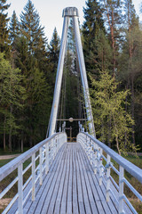 Wooden light hinged bridge across the river in a forest.