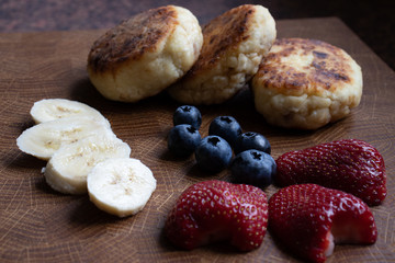 Delicious dessert of cheesecakes, berries and banana on a wood stand