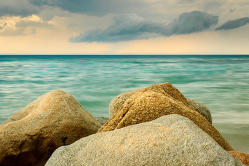 Scenic Kalogria beach rocks in a foreground, turquoise water and moody sky