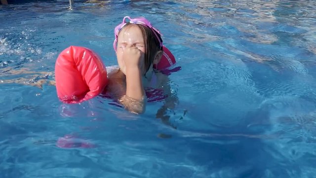 little girl with floaty swimming slow motion. A little girl tries to go face down in the pool and swim with the help of a floaty..