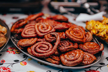 Roasted spiral sausages on a plate, close angle.