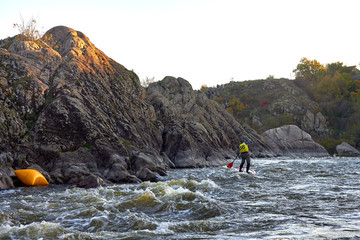 Man paddling whitewater on a a stand up paddle board