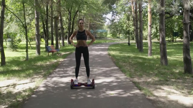 Beautiful girl with athletic body on hoverboard walking in park