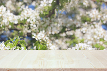 empty wooden table on a spring blurred background with flowering branches of Apple