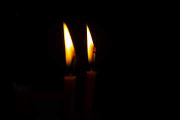 The flame of two burning candles on a dark background